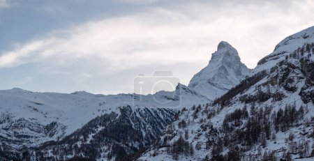 Téléchargez les photos : Vue aérienne de Zermatt, en Suisse, montre des chalets et des hôtels avec des toits de neige. Le sommet du Cervin se distingue, avec un chemin de fer à crémaillère serpentant à travers la ville contre les pentes enneigées et les montagnes. - en image libre de droit