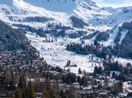Aerial panoramic view of the Verbier ski resort town in Switzerland. Classic wooden chalet houses standing in front of the mountains. 