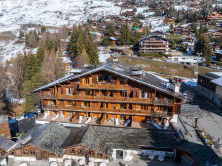 Luftaufnahme des Skiortes Verbier in der Schweiz. Klassische Holzchalet-Häuser vor den Bergen. 