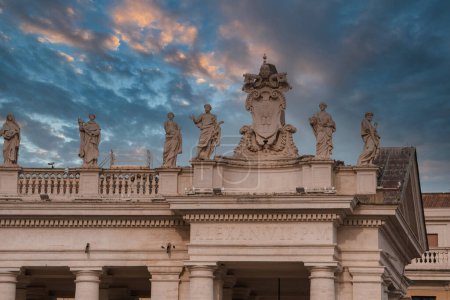 Architectural ensemble in Vatican City, possibly St. Peters Square. Sunrise or sunset lighting creates a golden backdrop to classical statues and grand facade with historical significance.