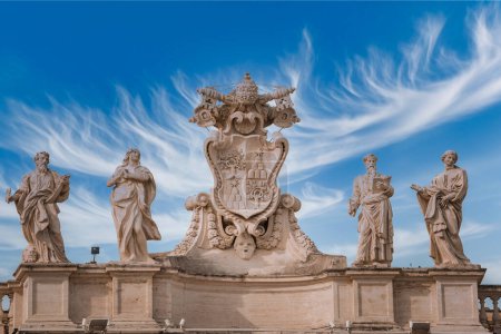 Statues with ornate coat of arms under a dramatic sky in Vatican City. Classical sculptures and symbolic imagery provide historical and religious significance.