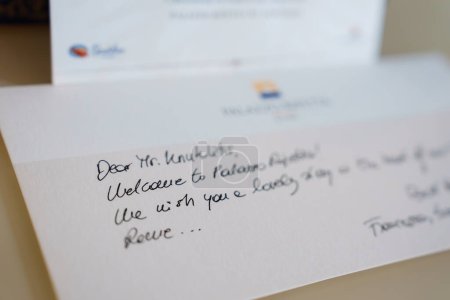 Close up handwritten welcome note to Mr. Knudsen at Palazzo Altemps, Rome, wishing a pleasant stay. Neat cursive writing with blurred hotel logo in background.