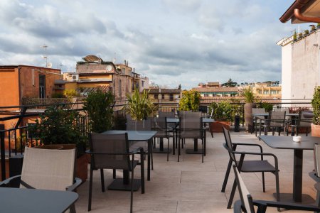 Foto de Roma hotel de lujo terraza en la azotea con muebles modernos, vegetación y horizonte de la ciudad en el fondo. Lugar ideal para los turistas para relajarse y disfrutar de las vistas. - Imagen libre de derechos