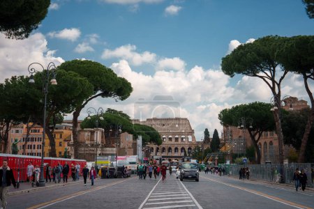 Téléchargez les photos : Scène de rue animée à Rome, Italie près de l'emblématique Colisée. Les piétons, les voitures, les pins et les barrières de construction ajoutent à l'atmosphère vibrante de la ville. - en image libre de droit