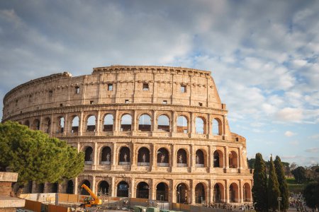 Kolosseum in Rom, Italien. Ikonisches antikes Amphitheater unter sanftem, bewölktem Tageslicht. Bogenförmige Ruinen mit Bauarbeiten, Touristen und Bäumen in der Nähe.