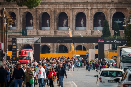 Téléchargez les photos : Scène urbaine dans une ville européenne avec une foule diversifiée marchant sur une rue historique bordée de véhicules et de panneaux commerciaux, mélangeant éléments classiques et modernes. - en image libre de droit