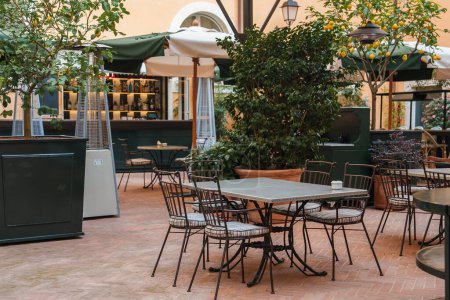 Luxushotel in Rom mit Terrakottafliesen, üppigem Grün, Zitronenbaum, schmiedeeisernen Stühlen und einer gut sortierten Bar. Entspanntes, elegantes Ambiente für Gäste.