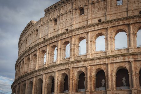 Nahaufnahme des berühmten Kolosseums in Rom, Italien. Mit Bögen, Säulen, Statuen und einer dramatischen Himmelskulisse. Roms alte Geschichte und architektonische Wunder umarmen.