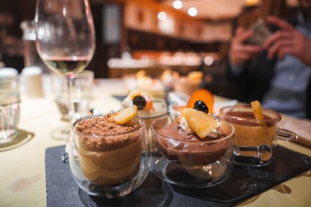 Köstliche Desserts auf einem Restauranttisch mit Mousse- und Pudding-Variationen mit verlockenden Beilagen. Warmes Ambiente, perfekt für ein genussvolles kulinarisches Erlebnis.