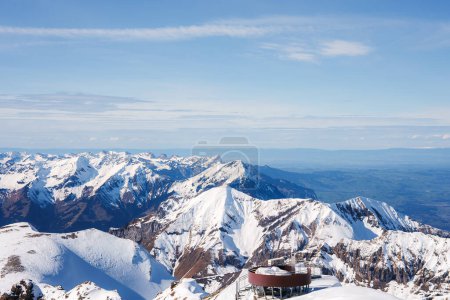 Atemberaubender Blick auf das Skigebiet Murren, Schweiz. Kreisförmiges Gebäude auf einem schneebedeckten Gipfel mit Blick auf die Schweizer Alpen unter klarem blauen Himmel. Ideal zum Skifahren und Snowboarden.