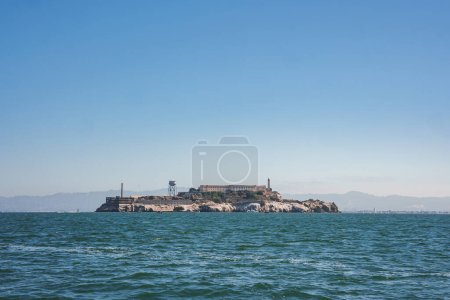 Alcatraz Island, San Francisco Bay, Kalifornien, USA. Ehemaliges Bundesgefängnis, felsige, karge Insel mit in die Jahre gekommenen Gebäuden. Wasserturm, Leuchtturm, blaues Wasser, Hügel, sonniger Himmel, Isolationsthema.