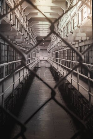 Innenansicht des Alcatraz-Gefängnisses in San Francisco, USA. Der Blick durch Maschendrahtzaun zeigt Zellenblöcke, vergitterte Türen und grelle Beleuchtung. vermittelt Isolation und historische Atmosphäre.