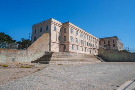 Vea la icónica prisión de Alcatraz en San Francisco, EE.UU., mostrando un gran edificio de color beige con múltiples ventanas, una entrada central y dos juegos de escaleras.