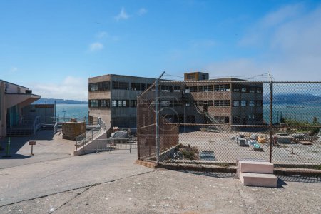 Escena que muestra la abandonada prisión de Alcatraz en San Francisco, Estados Unidos. La zona vallada al aire libre y el edificio en ruinas evocan una sensación de aislamiento e historia.