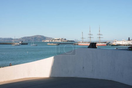 Foto de Serena vista frente al mar en San Francisco con barcos y veleros históricos, paisaje montañoso, cielo azul. Posiblemente cerca del muelle 39, no mostrando el puente Golden Gate. - Imagen libre de derechos
