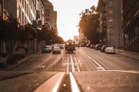 Téléchargez les photos : Vivez un moment magnifique dans une rue pittoresque de San Francisco pendant l'heure d'or. Téléphériques classiques et charmante architecture préparent le terrain. - en image libre de droit