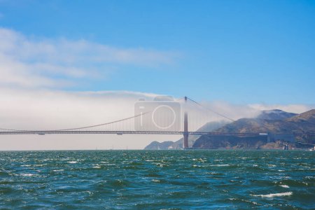 Ikonische Golden Gate Bridge in San Francisco, Kalifornien. Bild von einem Aussichtspunkt über das abgehackte Wasser der Bucht, das die von charakteristischem Nebel umhüllte Brücke zeigt.