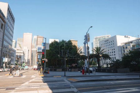 Téléchargez les photos : Scène de rue urbaine à San Francisco, CA. Ciel dégagé, ombres ensoleillées sur les bâtiments modernes. Traversée piétonne, pistes de téléphérique, atmosphère calme. - en image libre de droit