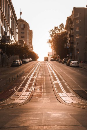 Photo for Serene moment in San Francisco iconic cable car tracks under a golden sunset. Peaceful scene with classic buildings and parked cars bathed in warm light. - Royalty Free Image