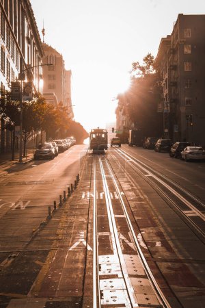 Photo for Scenic San Francisco street at sunrise or sunset with cable car, parked cars, and buildings of varying architectural styles evoking citys charm and nostalgia. - Royalty Free Image
