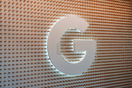 Photo for Large, backlit letter G in modern font against a textured wooden wall. Warm contrast of natural wood finish with soft glow. Possible commercial interior design. - Royalty Free Image