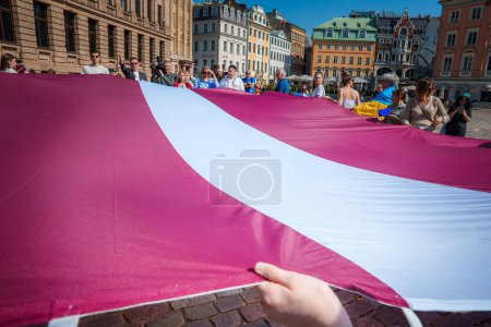 Photo for Celebrate Latvias EU anniversary in Riga with a vibrant flag filled scene in the old town. Smiling faces, historic facades, and unity under clear skies. - Royalty Free Image