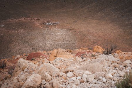 Entdecken Sie die felsige Landschaft des Meteor Crater, Arizona, USA. Braune und beige Felsbrocken zeichnen eine zerklüftete Szenerie, in der Erosionen sichtbar werden. Erkunden Sie dieses ikonische geologische Wunder.