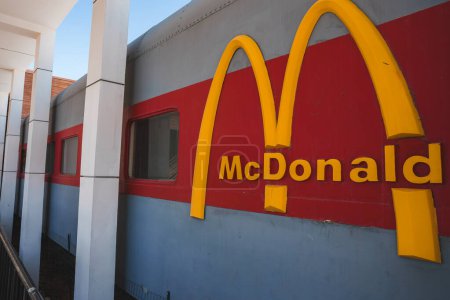 Foto de Iconic McDonalds logo on a train car structure in Barstow, USA. Gris con acentos rojos o blancos que recuerdan al tema Americana y Ruta 66, bajo cielos soleados. - Imagen libre de derechos
