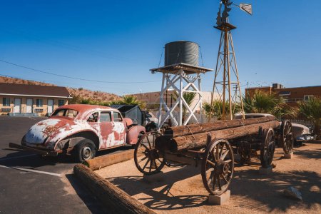 Photo for Vintage scene in Barstow, USA w or old wooden wagon, rusty Beetle car, windmill, and motel. Nostalgic nod to Route 66 travel culture. Sunny day, desert vibe. - Royalty Free Image
