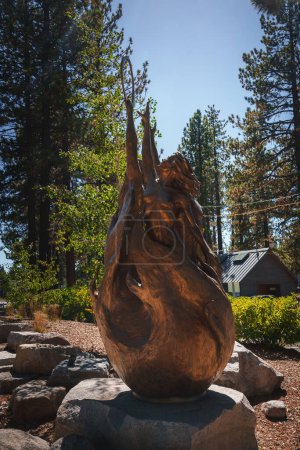 Photo for Dynamic bronze sculpture in outdoor setting with pine trees, glowing in sunlight. Intricate details and graceful form create a peaceful, contemplative atmosphere in Tahoe. - Royalty Free Image