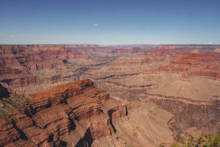 Panoramic view of the Grand Canyon in Arizona, USA, showcasing its colorful layers of sedimentary rock under a clear blue sky. A stunning natural landmark.