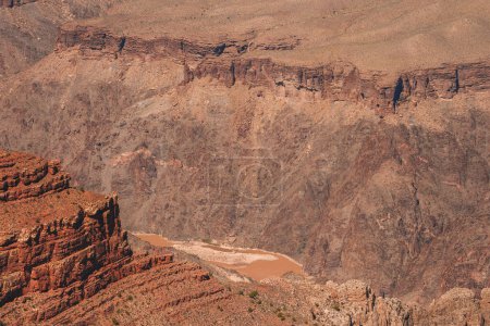 Schroffe Canyon-Landschaft mit geschichteten Felsformationen in rotbraunen Farbtönen, die Erosionsmuster aufweisen. Erinnert an den Grand Canyon, USA. Majestätische natürliche Umgebung.