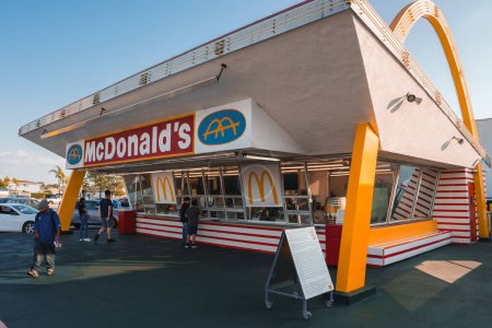 Foto de Estilo clásico americano McDonalds en Los Ángeles, que recuerda a la década de 1950. Icónicos arcos dorados, diseño rojo y blanco, clientes caminando en un día soleado. - Imagen libre de derechos