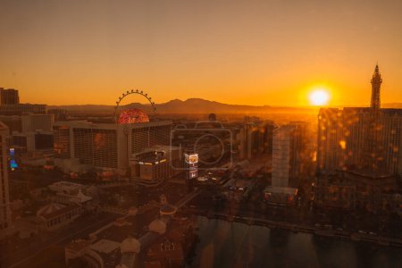 Photo for Vibrant Las Vegas Strip sunset captures iconic observation wheel and Eiffel Tower silhouette against warm cityscape. Shadows lengthen as day fades to evening under clear, radiant sky. - Royalty Free Image