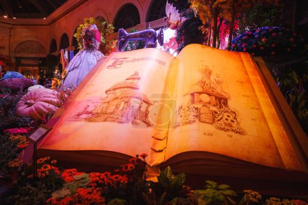 Photo for Large open book with illustrated pages, part of indoor display in themed setting, possibly in Las Vegas. Pages show castle sketches in magical ambiance with floral decor. - Royalty Free Image