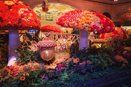 Photo for Vibrant indoor garden with oversized mushroom structures, colorful flowers, wooden fence, and acorn lamp creating a fairy tale atmosphere. Las Vegas luxury resort ambiance. - Royalty Free Image