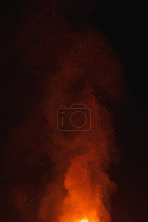 Espectáculo ardiente en el cielo nocturno del desierto con llamas brillantes y columna de humo, destacando el calor y el contraste entre el fuego y la oscuridad. Ideal para temas de festivales.