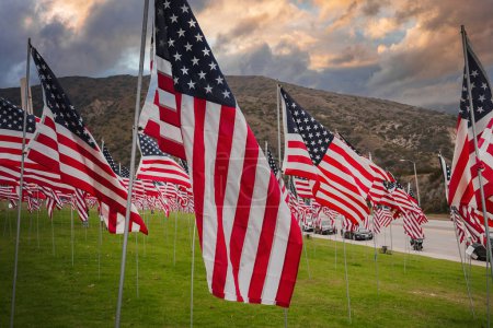 Foto de Banderas estadounidenses icónicas ondeando en el viento en medio de un paisaje montañoso de California bajo un cielo parcialmente nublado. Una escena patriótica de recuerdo y orgullo. - Imagen libre de derechos