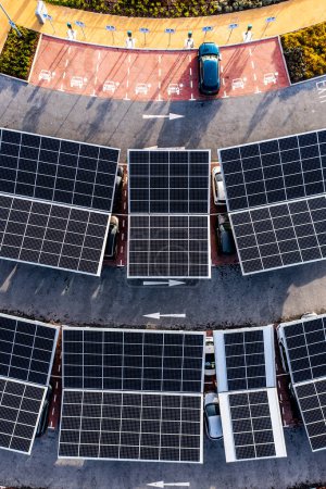 Photo for Aerial view directly above electric cars parking under solar panels on a parking lot rooftop ready for charging - Royalty Free Image