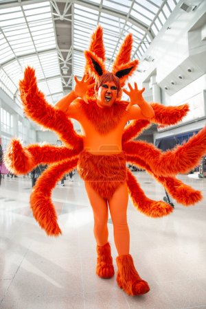 Foto de Un cosplayer masculino feliz vestido como un colorido personaje de anime japonés naranja en un evento cómico con el Reino Unido - Imagen libre de derechos