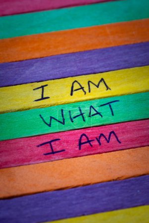 Photo for A hand written note representing gay pride stating I am what I am on a rainbow flag background in defiance of discrimination - Royalty Free Image