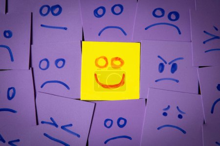 Photo for A positive or optimistic attitude concept with a bright and cheerful happy face drawn on sticky note surrounded by despair and grief.  Look on the bright side of life - Royalty Free Image