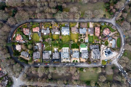 Téléchargez les photos : Une vue aérienne directement au-dessus d'un ensemble de logements circulaires avec des maisons exclusives et de l'herbe verte luxuriante pendant la sécheresse estivale et l'interdiction des tuyaux d'arrosage - en image libre de droit