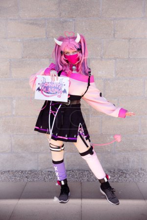 Foto de Una chica bonita cosplayer vistiendo un traje de anime japonés con pelo rosa y mascarilla en un evento cómico con el Reino Unido - Imagen libre de derechos
