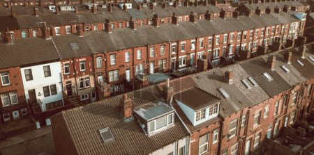 An aerial view above the rooftops of run down back to back terraced houses on a working class housing estate in the North of England