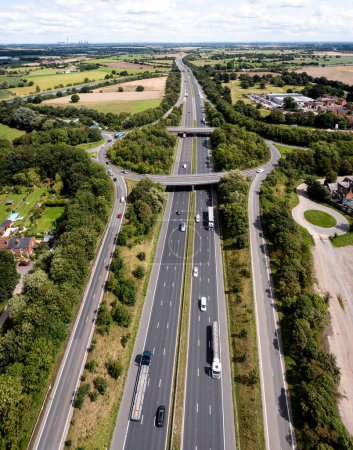 Photo for Aerial vertical panorama directly above a busy road intersection cutting through countryside on the M62 motorway heading East towards Hull in the UK - Royalty Free Image