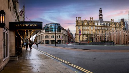 Foto de CITY SQUARE, LEEDS, Reino Unido - 14 DE NOVIEMBRE DE 2023. Paisaje panorámico de edificios históricos incluyendo el Queens Hotel en la zona peatonal en City Square en Leeds, West Yorkshire al atardecer - Imagen libre de derechos