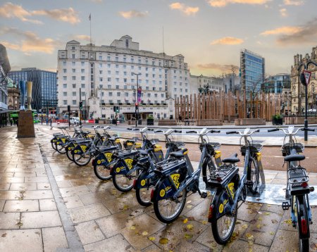 Foto de CITY SQUARE, LEEDS, Reino Unido - 14 DE NOVIEMBRE DE 2023. Una fila de bicicletas de alquiler en la zona peatonal y de bajas emisiones de City Square en Leeds, West Yorkshire al atardecer - Imagen libre de derechos