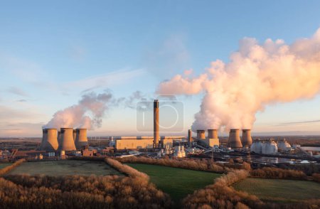Planta de energía a carbón Drax en Yorkshire del Norte, Reino Unido con pila de carbón y tanques de almacenamiento de biomasa al atardecer con espacio para copias