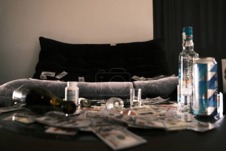 Foto de Escena con sofá y mesa dispersa Bebida alcohólica, pastillas, aguja, drogas. Dineros y tarjetas. Concepto de narcóticos y adicción - Imagen libre de derechos